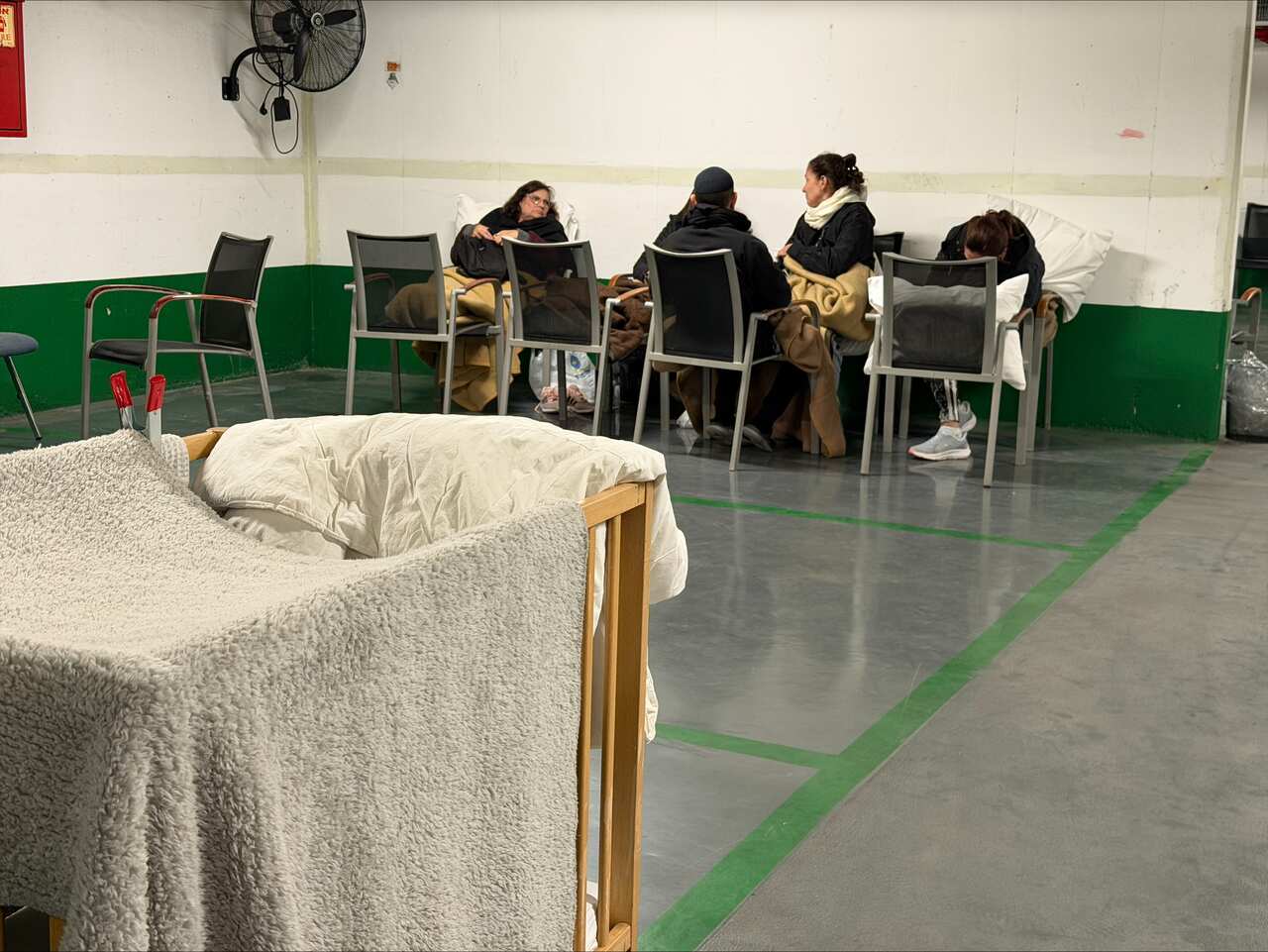 People sitting on chairs in an underground car park.