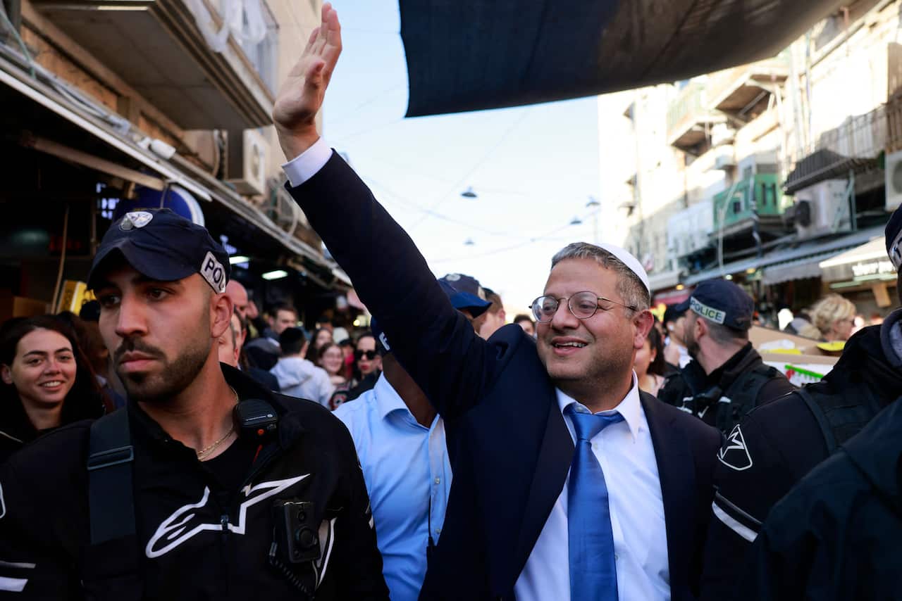 Itamar Ben Gvir waves to supporters in a crowded market in Jerusalem.