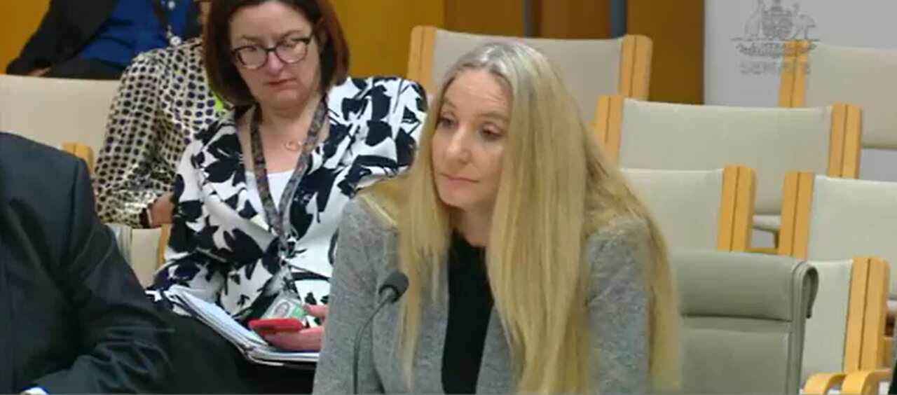 A woman sitting down in front of a microphone at a desk.