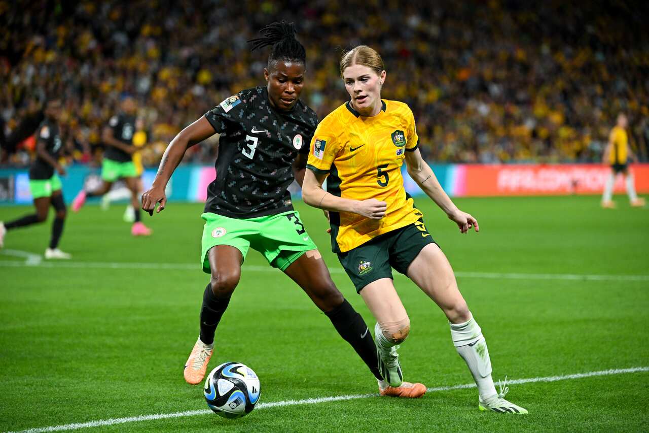 Two football players from opposing teams fight for the ball.