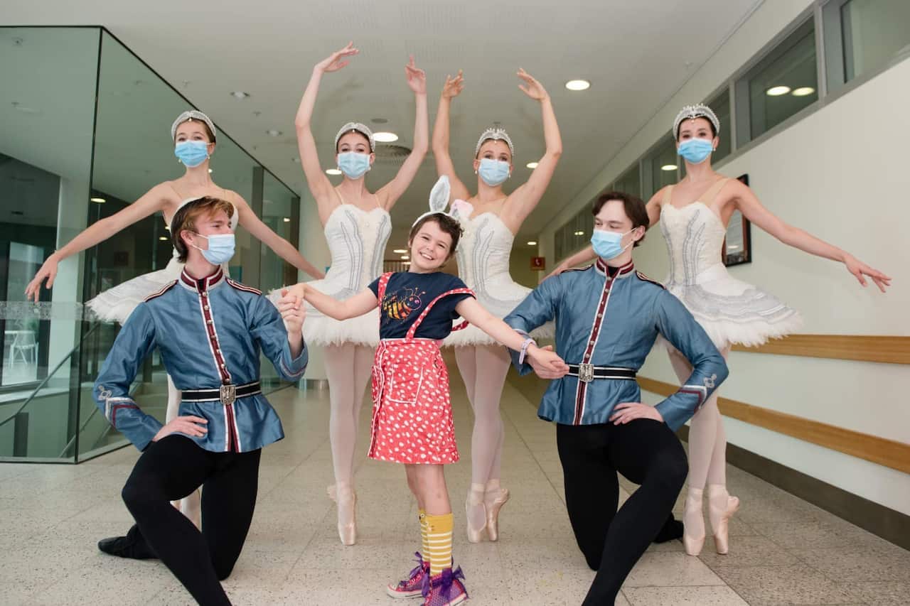 Ballet dancers strike a pose with a child patient in bunny ears.