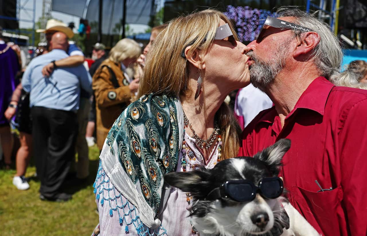 A couple kissing while wearing solar eclipse safety glasses