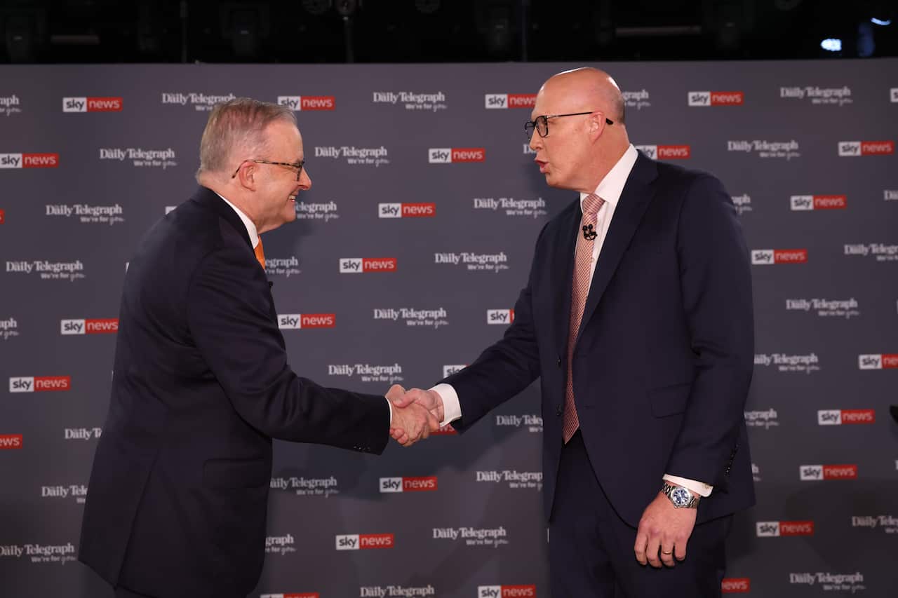 Two men in suits shake hands in front of a black background with Sky News logos.
