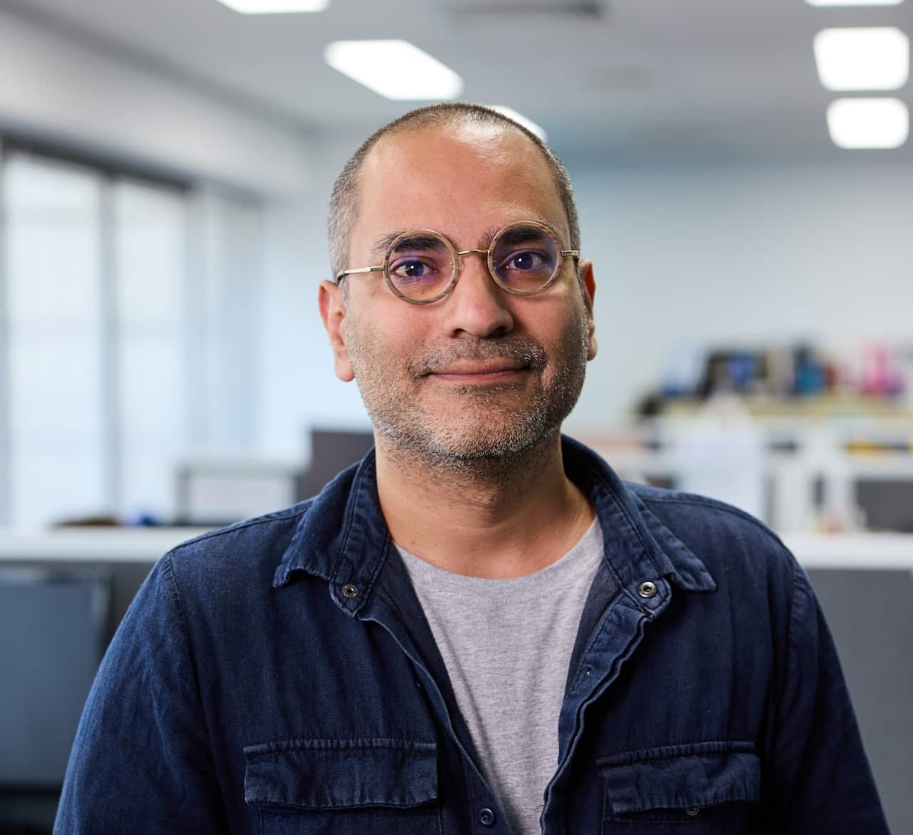 A man wearing glasses in an office looking at a camera