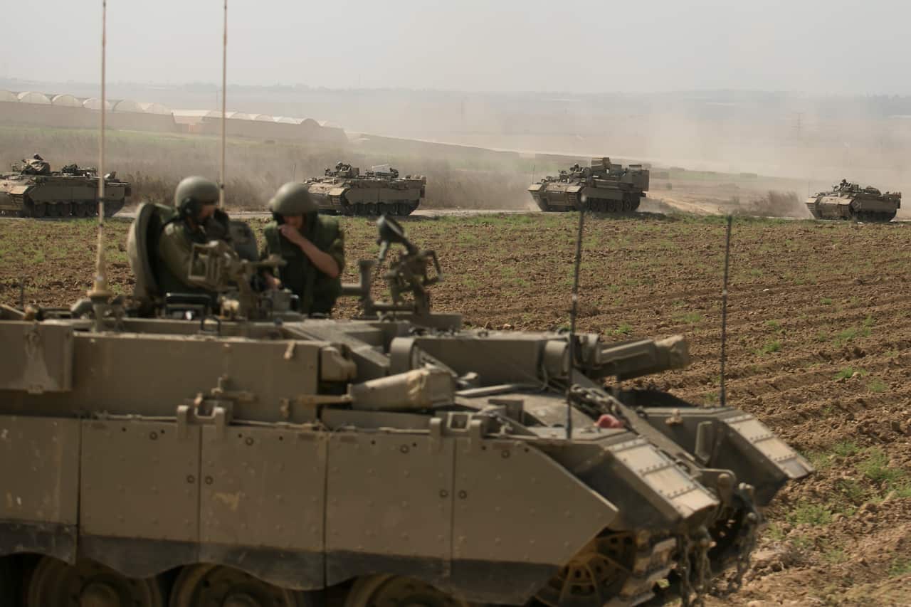 Tanks being driven by soldiers along a dirt track.