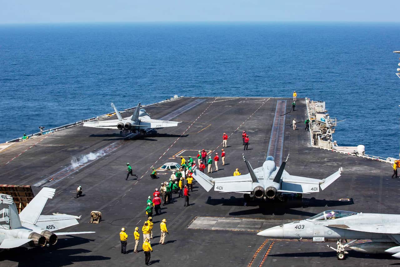 Aircraft prepare to fly out from a warship at sea.
