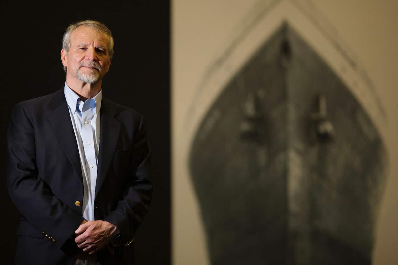 A man in a suit and tie looks at the camera.