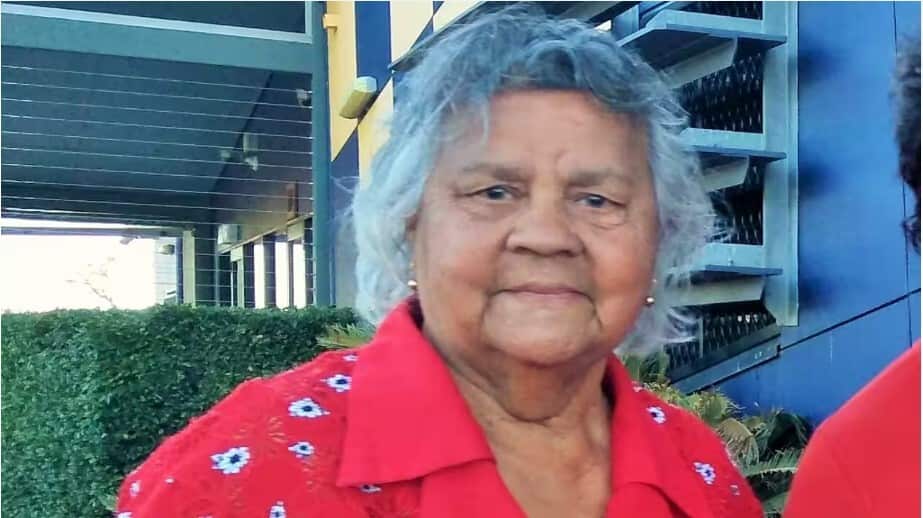 An older woman outside wearing a red shirt.