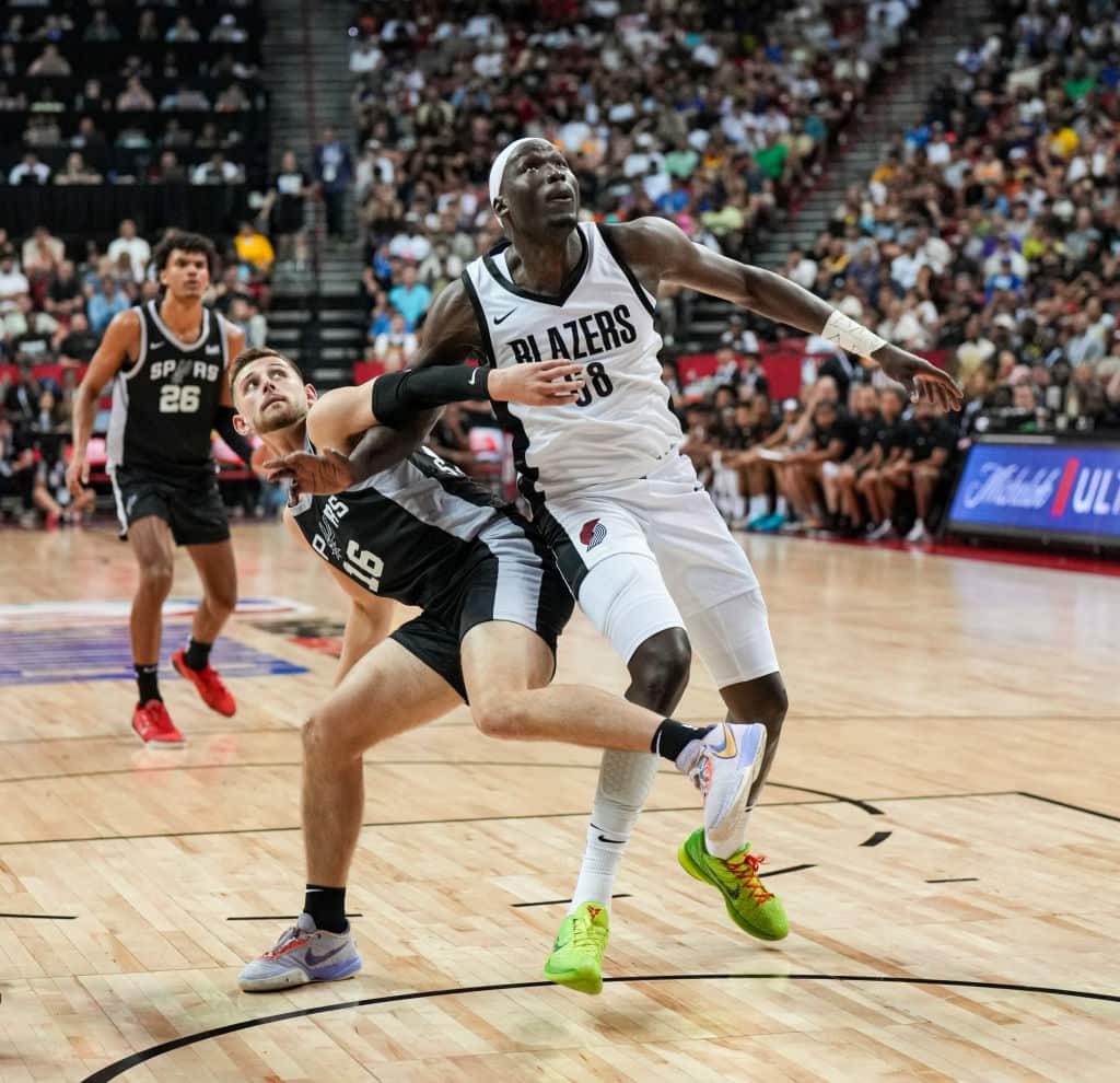A man in a white basketball uniform pushes against a man in a black basketball uniform on the court 