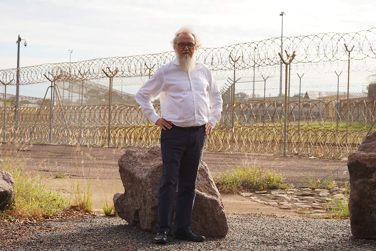 John Lawrence standing in front of barbed-wire fencing outside Don Dale Detention Centre