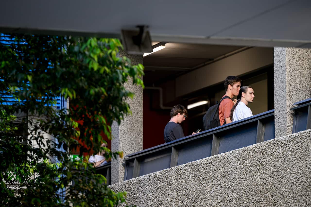 A small group of students gather outside classrooms.