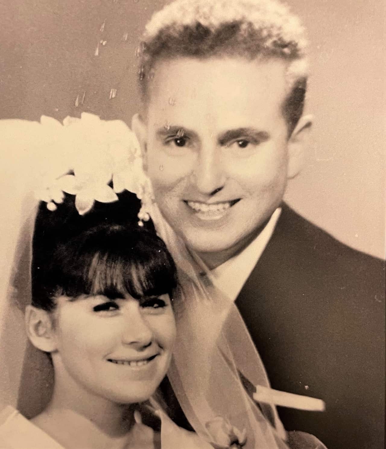 A woman in a wedding veil stands next to a man in a suit.