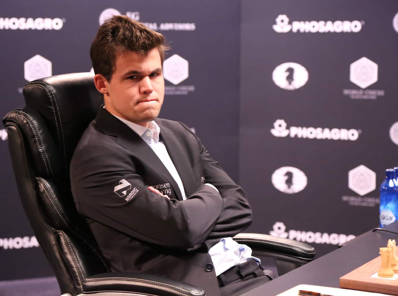Magnus Carlsen sitting in a chair with his arms crossed