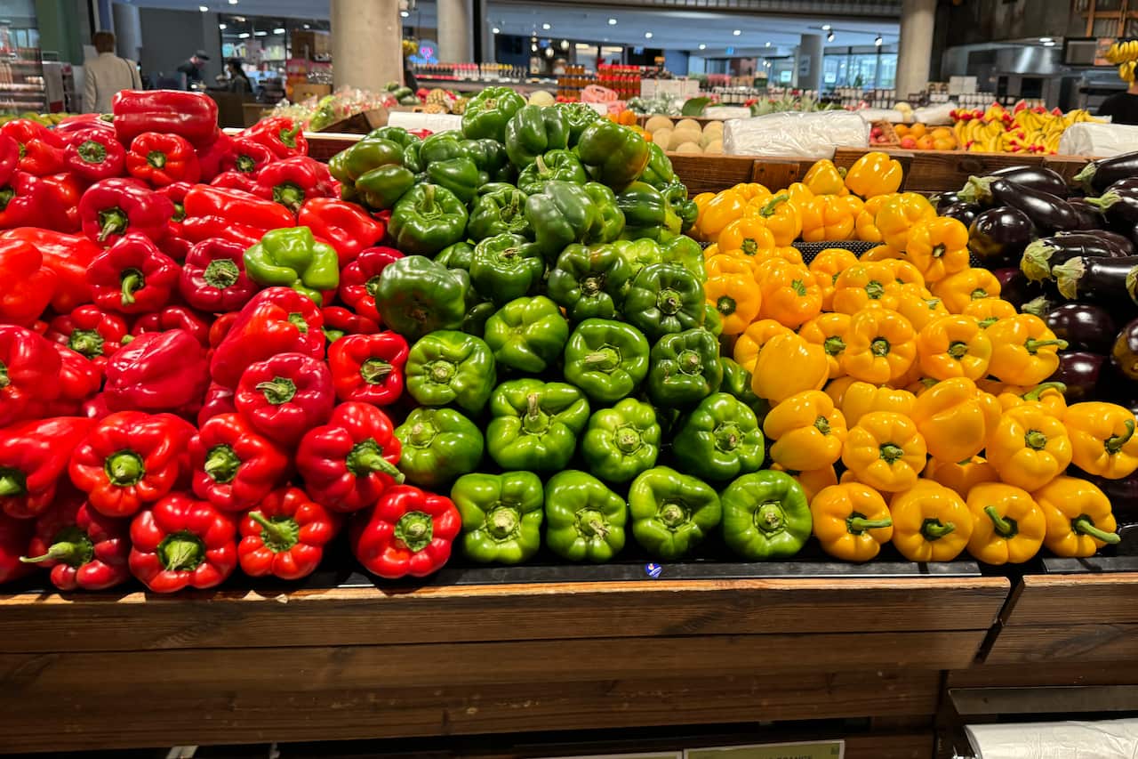 Red, green and yellow capsicums at a supermarket.