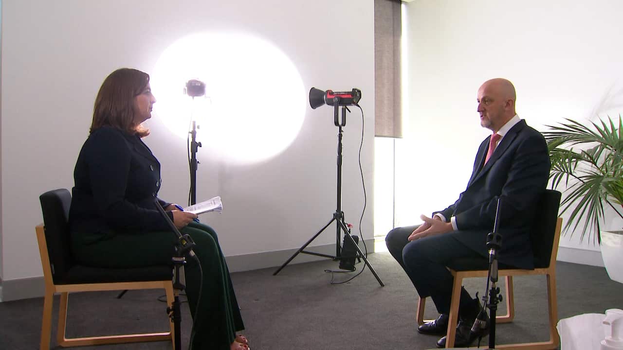 A man and a woman sitting opposite each other, conducting a TV interview