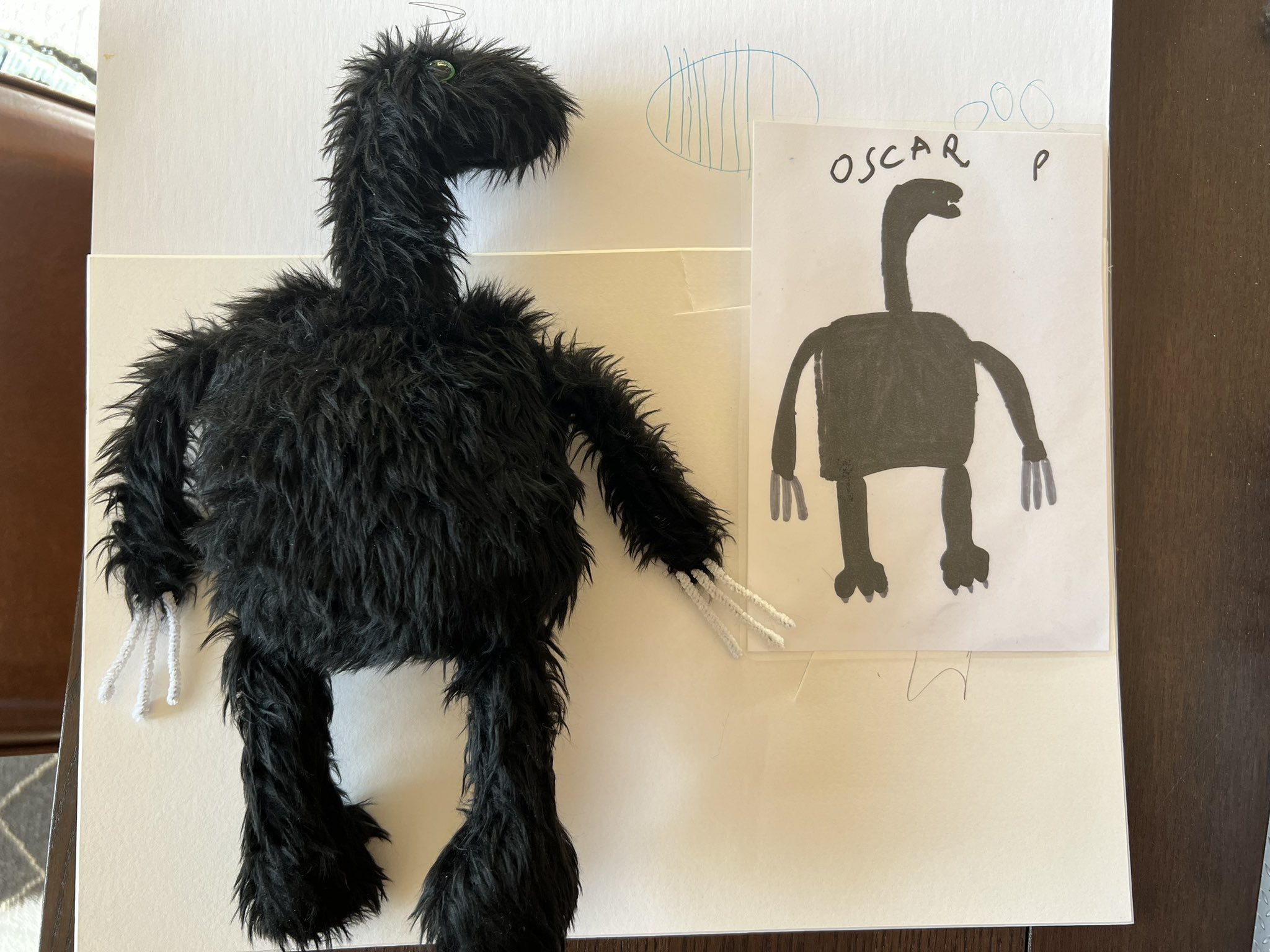 Black furry monster next to drawing of black animal. 
