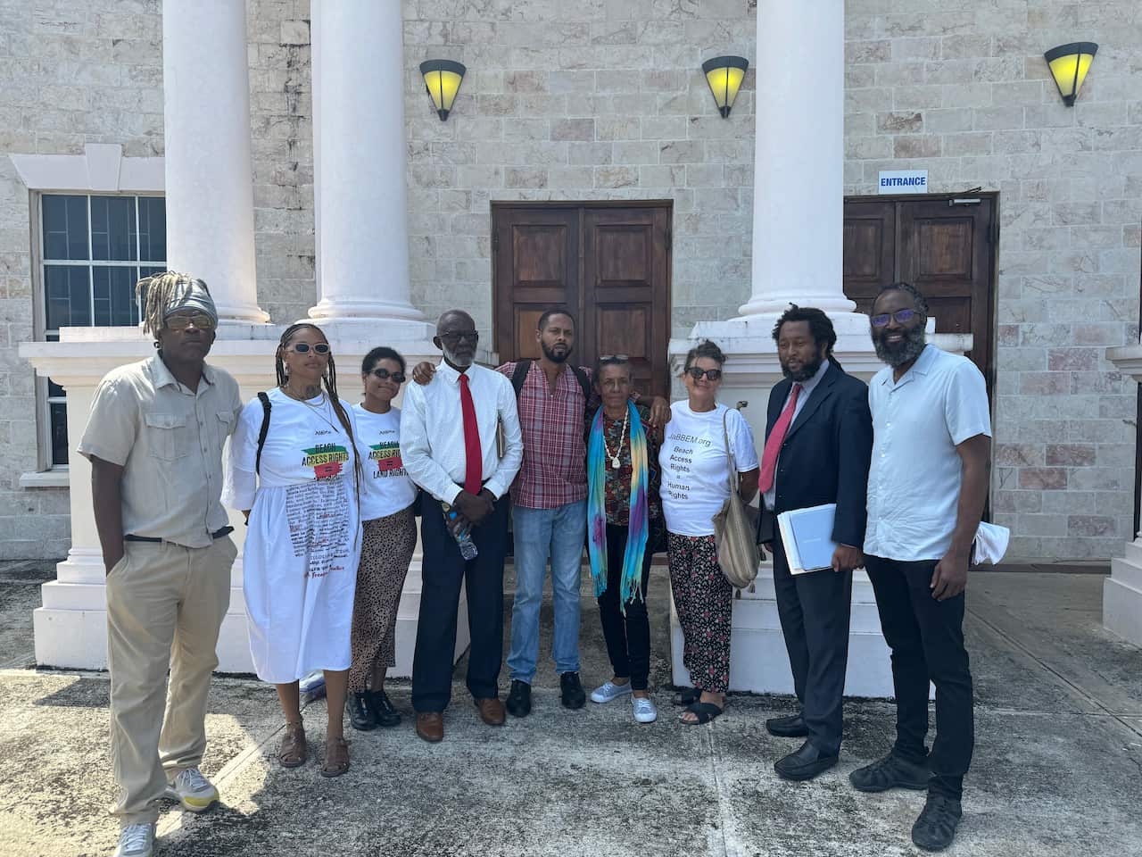 Nine people stand before a courthouse 