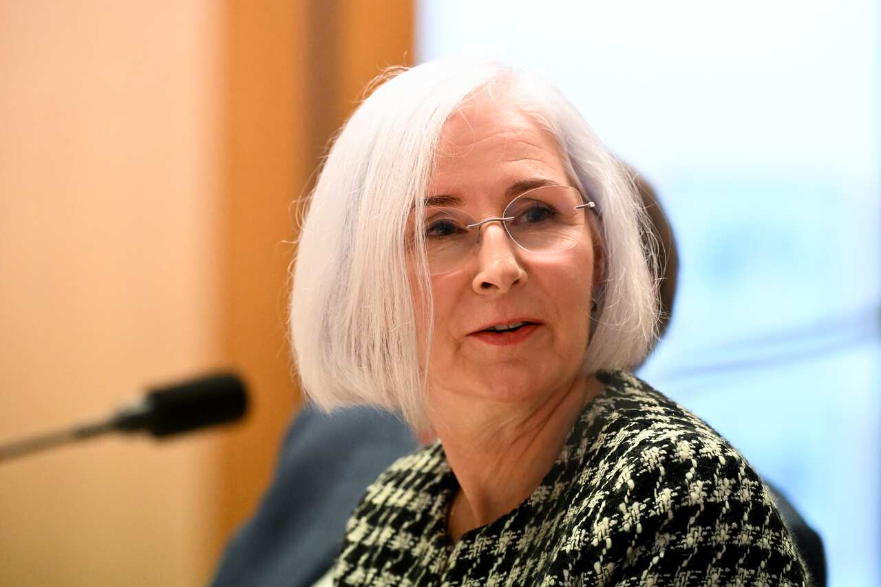A woman speaking in front of a microphone while seated.