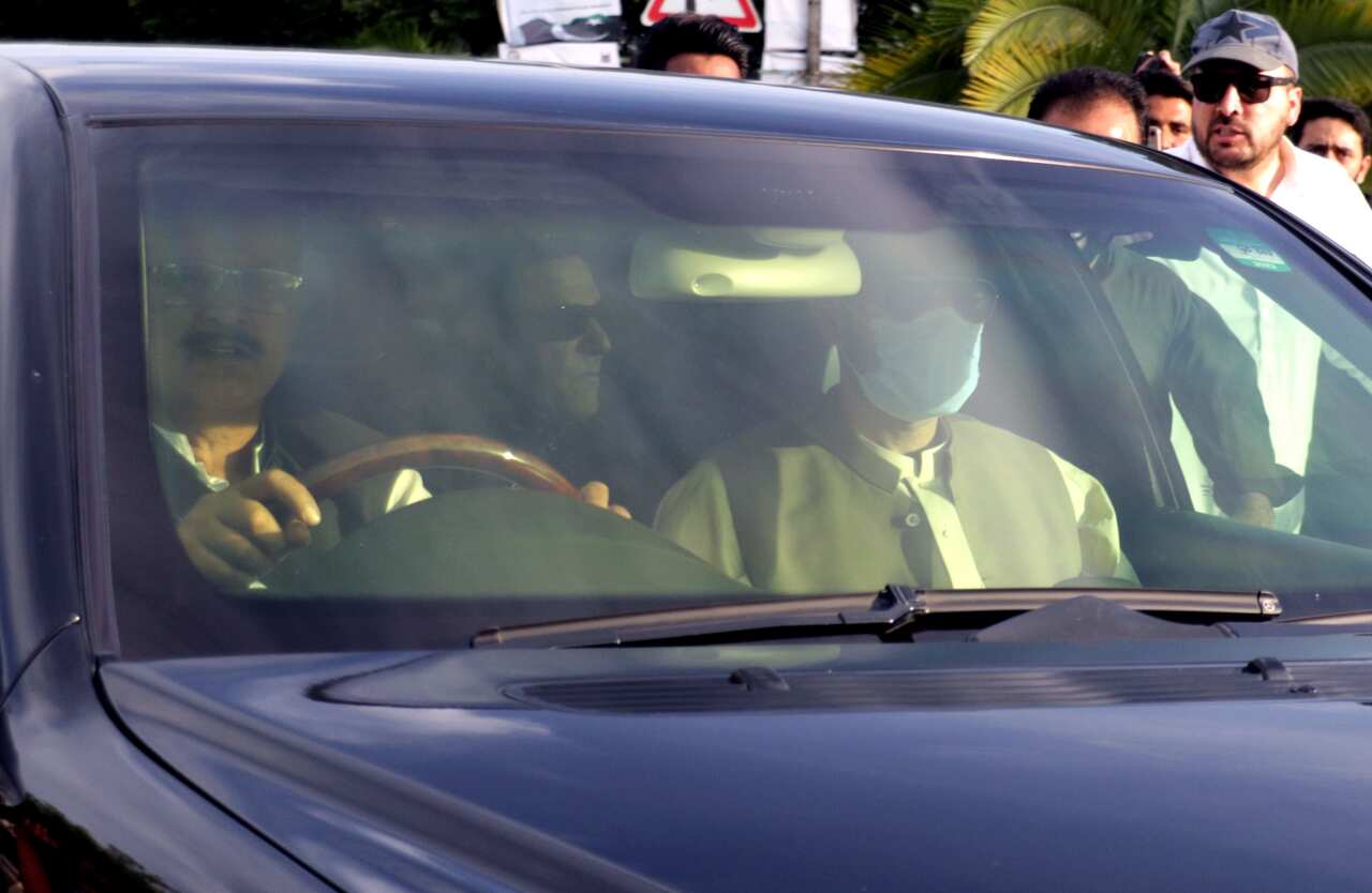 Former Prime Minister Imran Khan wearing sunglasses in the back of a car, travelling to the Supreme Court after it ordered his release.