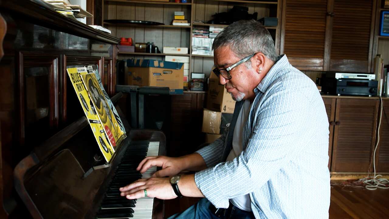 Simon playing the piano in his home.