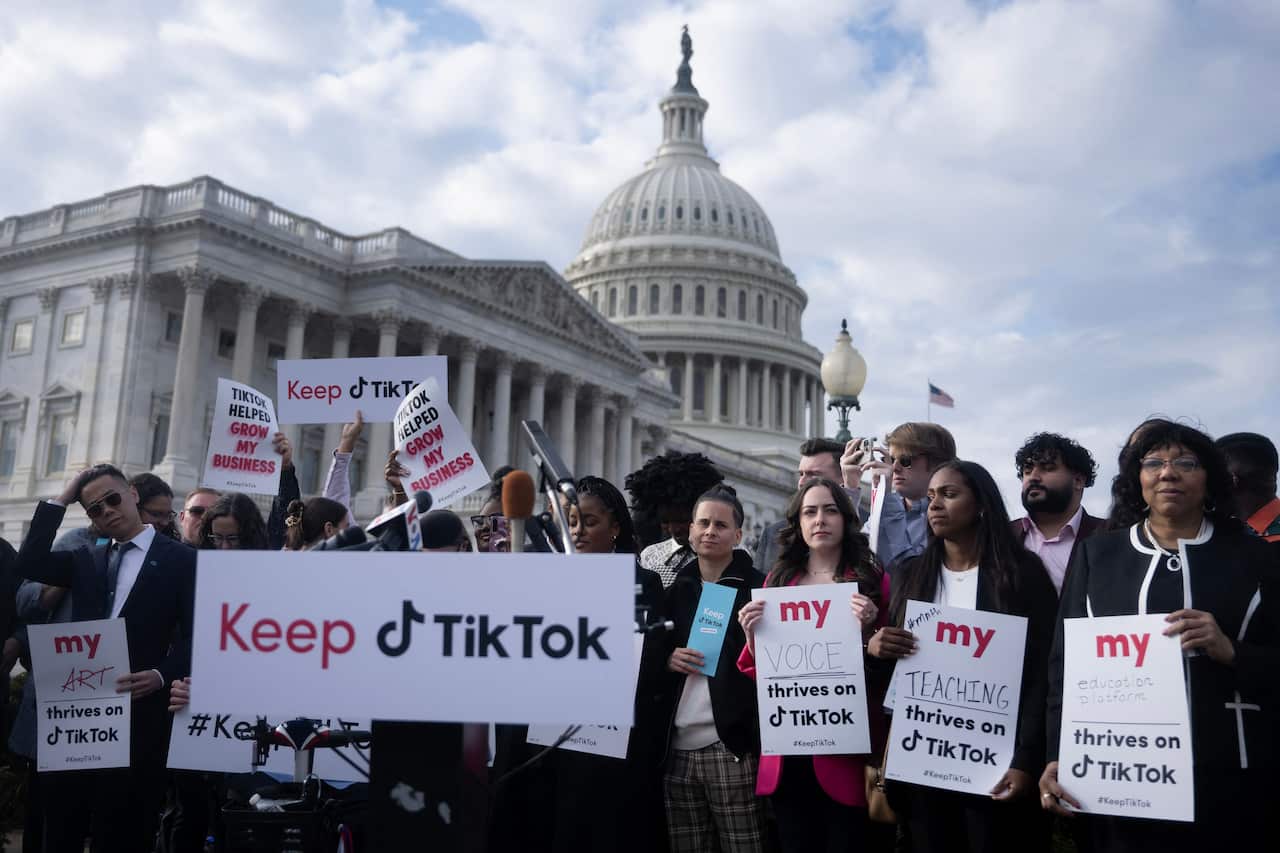 People protest with signs against a TikTok ban.