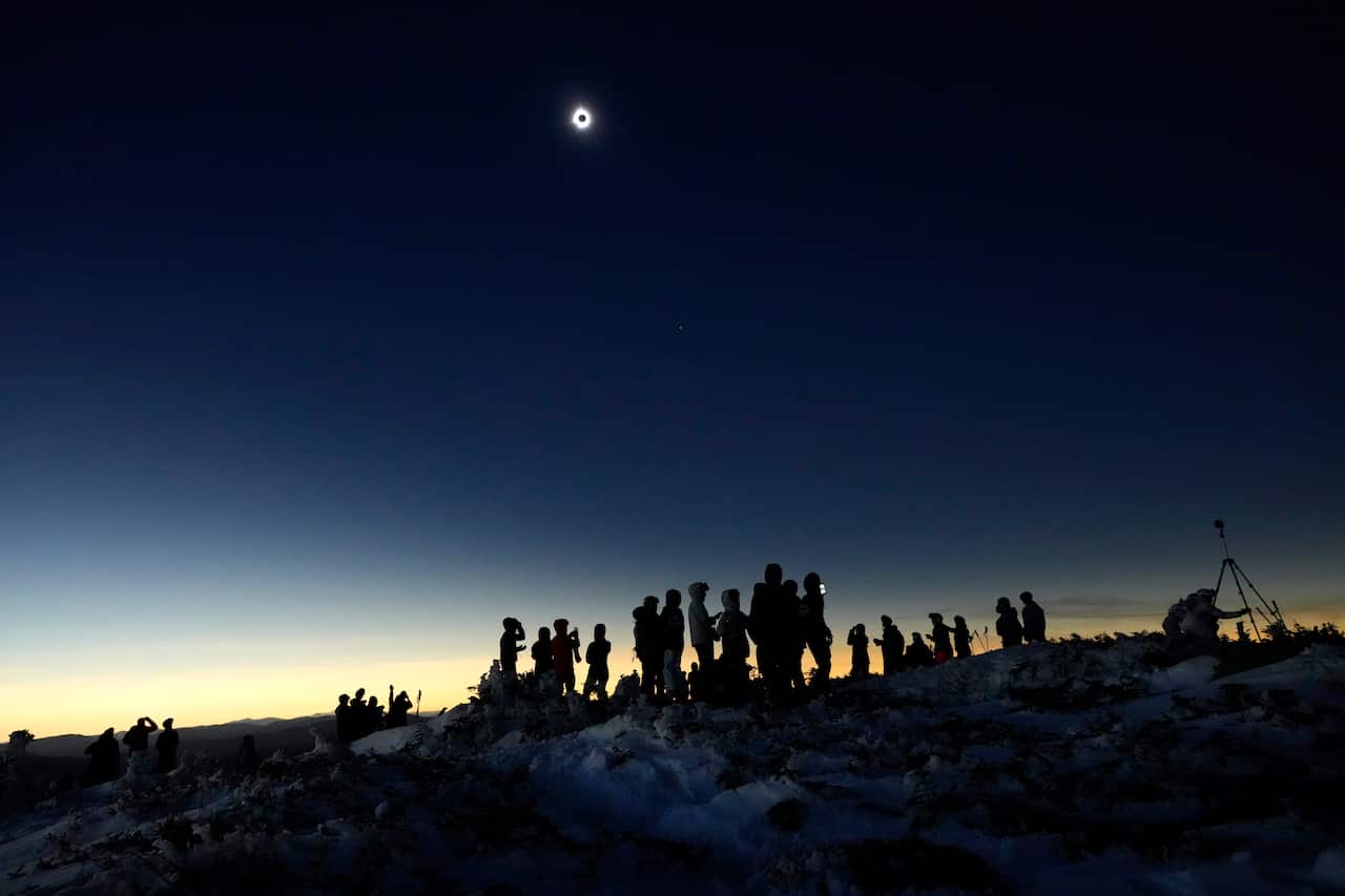 Hikers on a mountain looking at eclipse