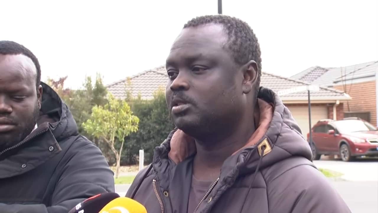 A man in a jacket addressing media