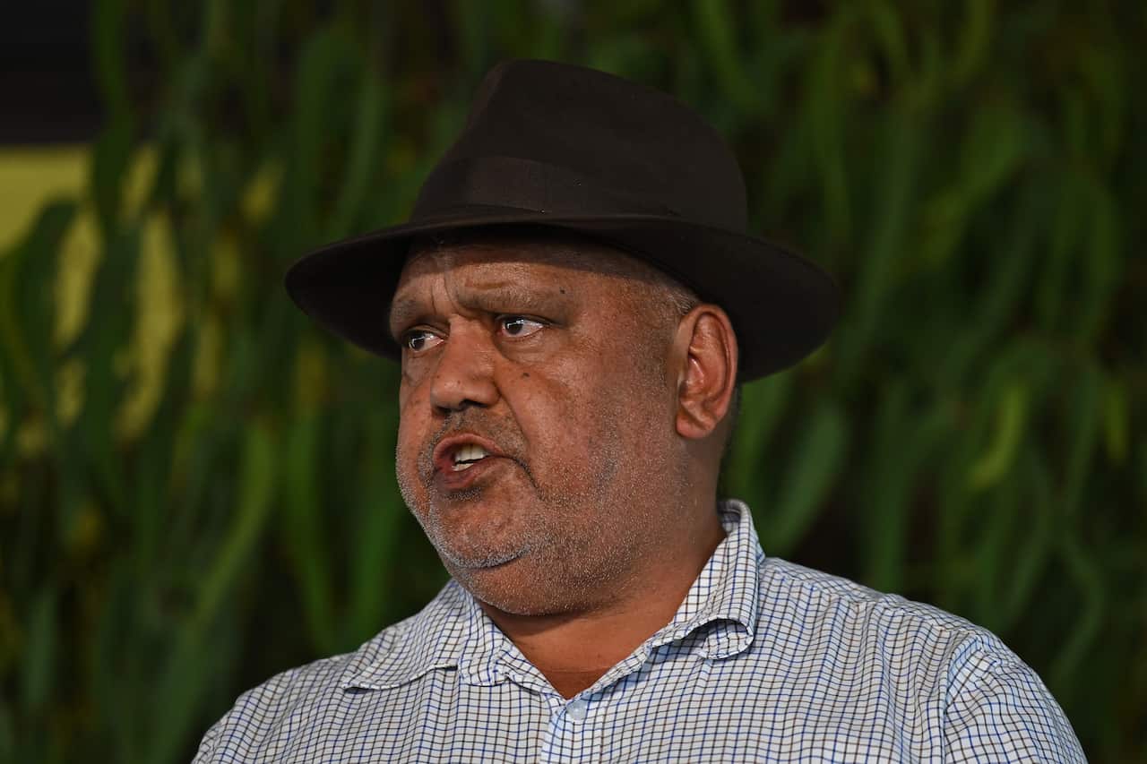 An older Indigenous man in a dark fedora hat and blue check shirt.
