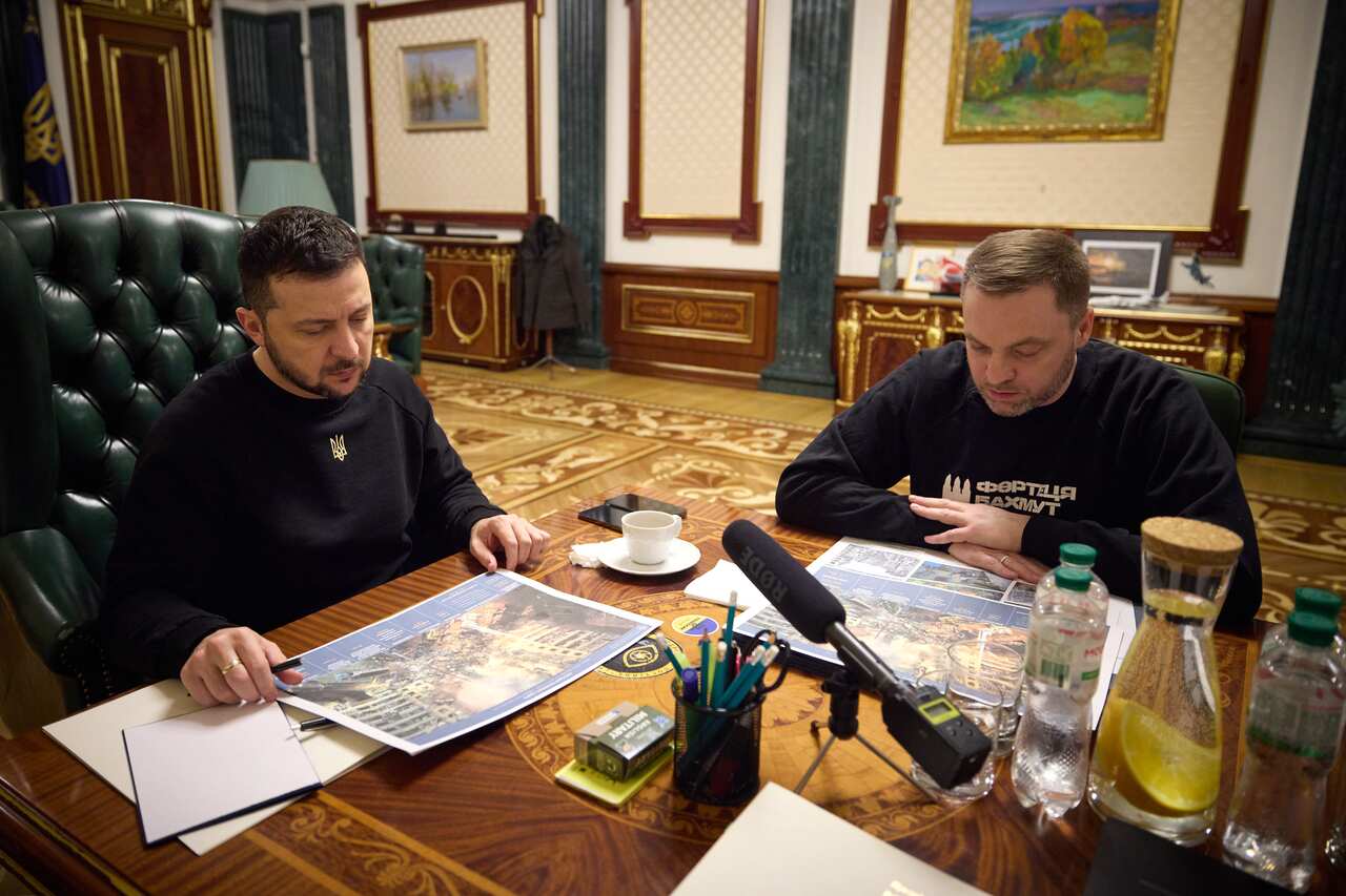 Two men sitting at a desk and looking at maps