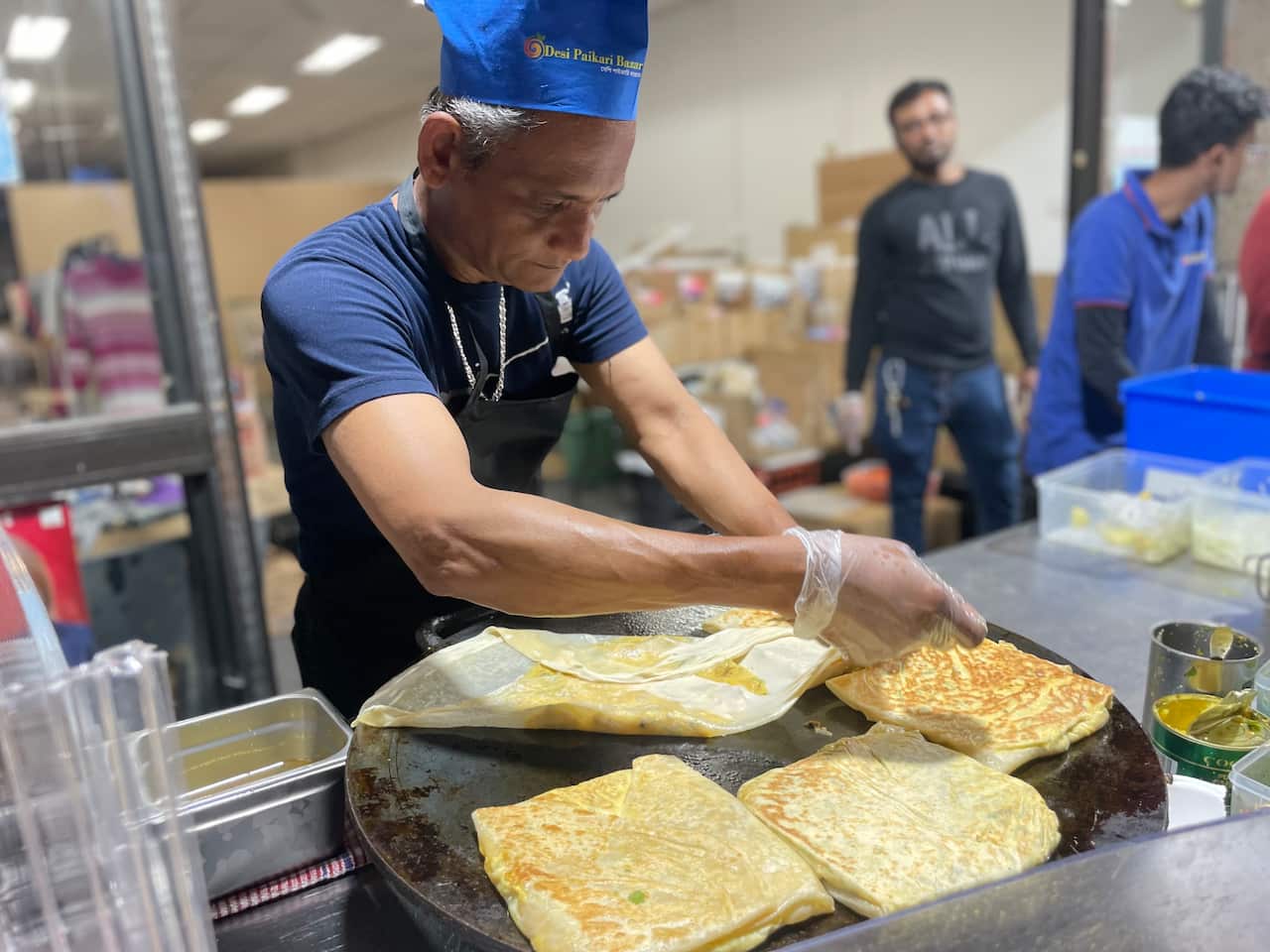 Murtabak being folded on a griddle by a merchant. 