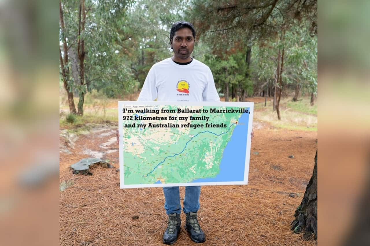 A man holds a map showing the path of his walk from Ballarat to Sydney.