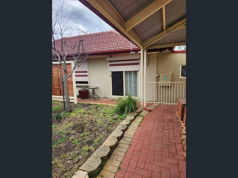 A red brick paved path under a verandah
