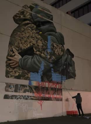 Man paints over a mural. 