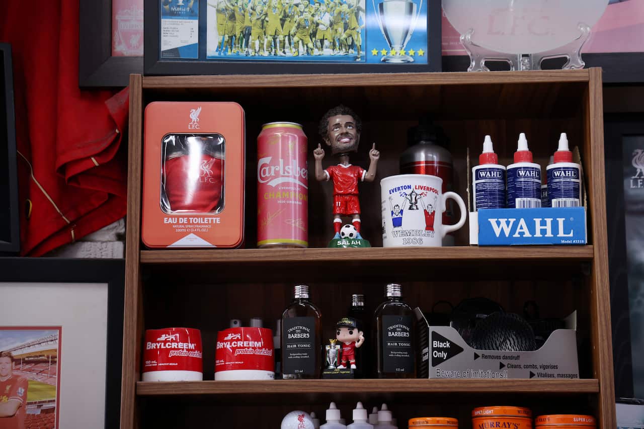A shelf of Liverpool FC memorabilia, including a figurine of Mohamed Salah, reflects Kleames Dawod's lifelong passion for the club inside his Sydney barbershop.
