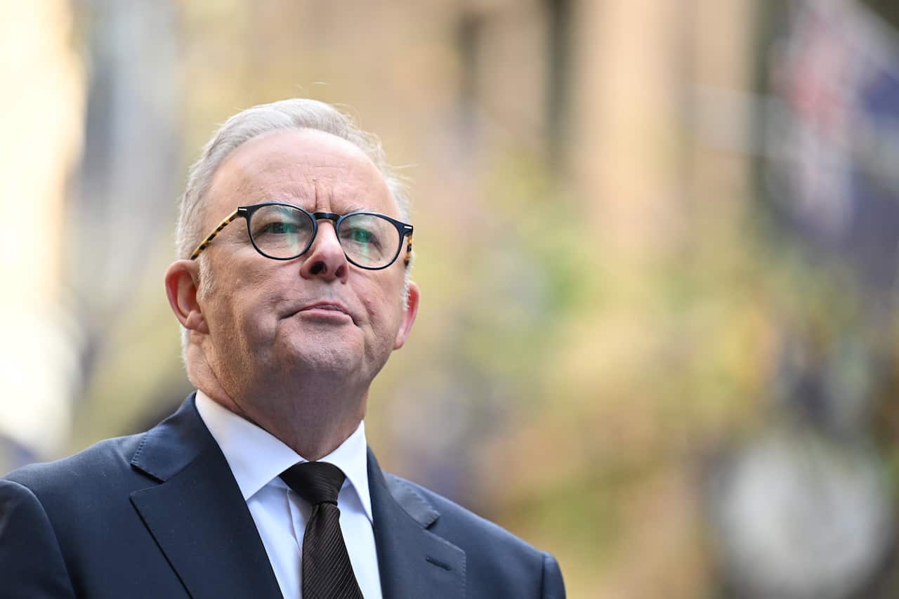 A man in a blue suit and grey hair and glasses.