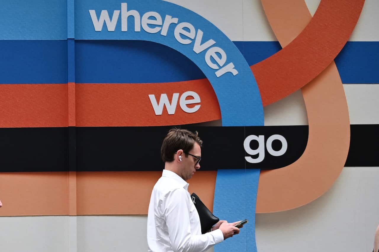 A man walking past a mural that says 'wherever we go'.