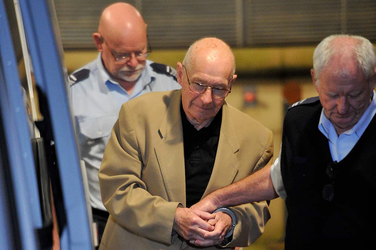 Rogers Rogerson in handcuffs being led by a corrections officer