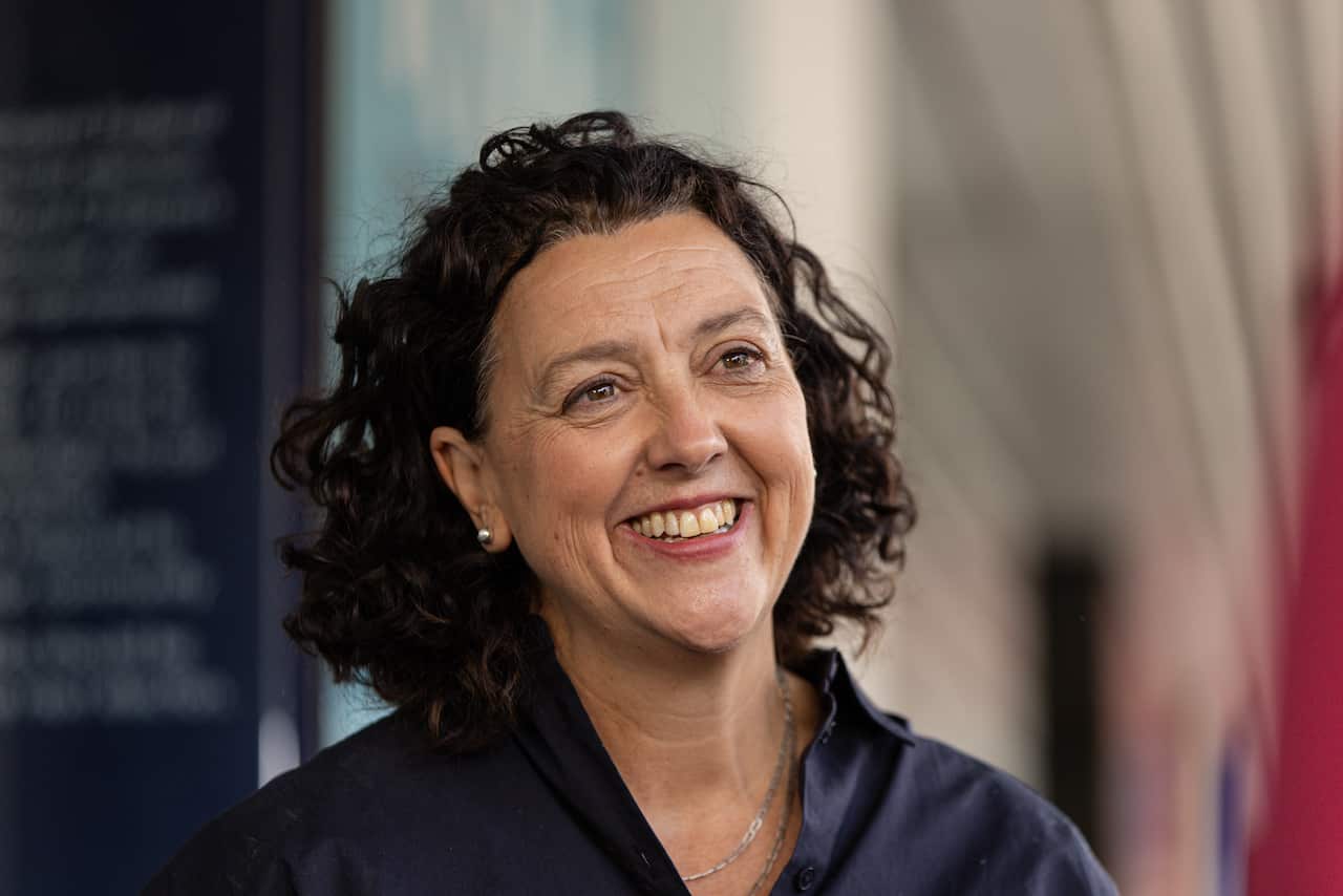 A woman with curly brown hair smiling. 