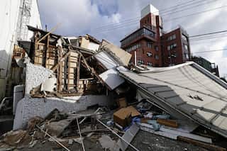 A house that has collapsed in an urban area. Rubble litters the ground.