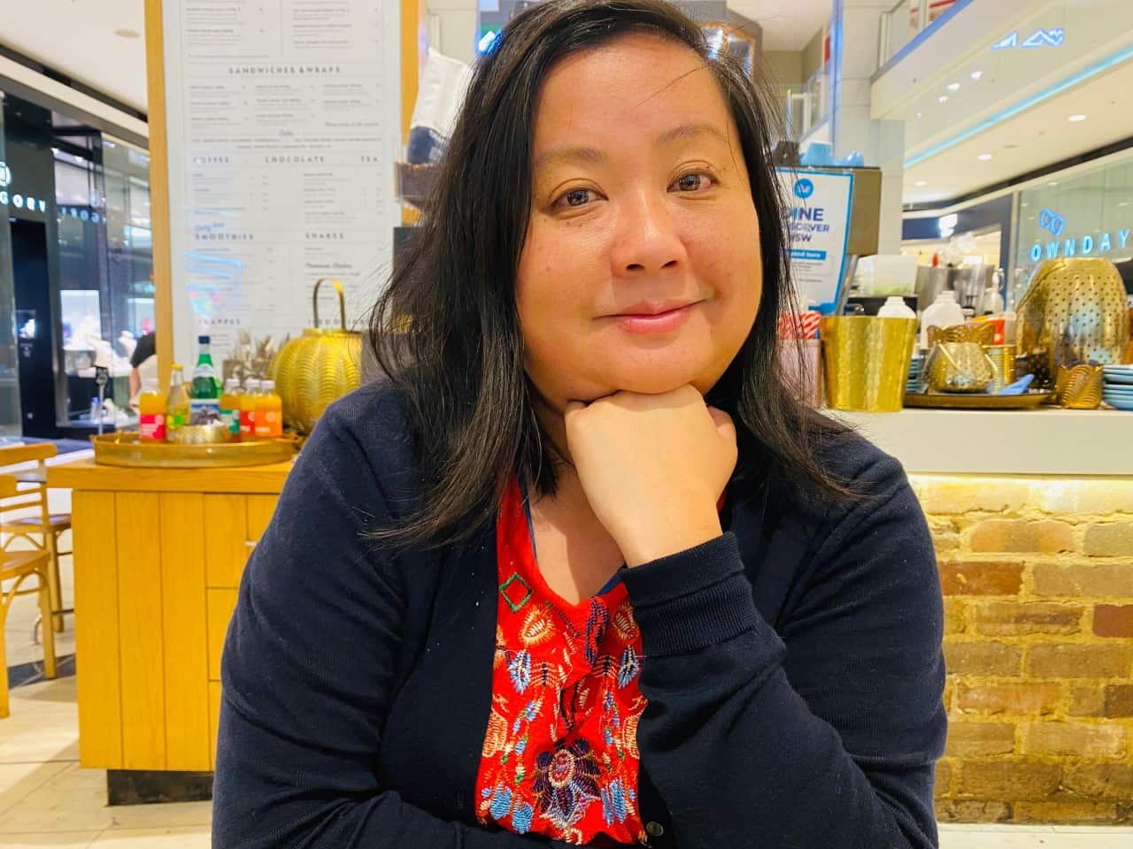 Woman sitting inside a cafe with her arm resting on her chin