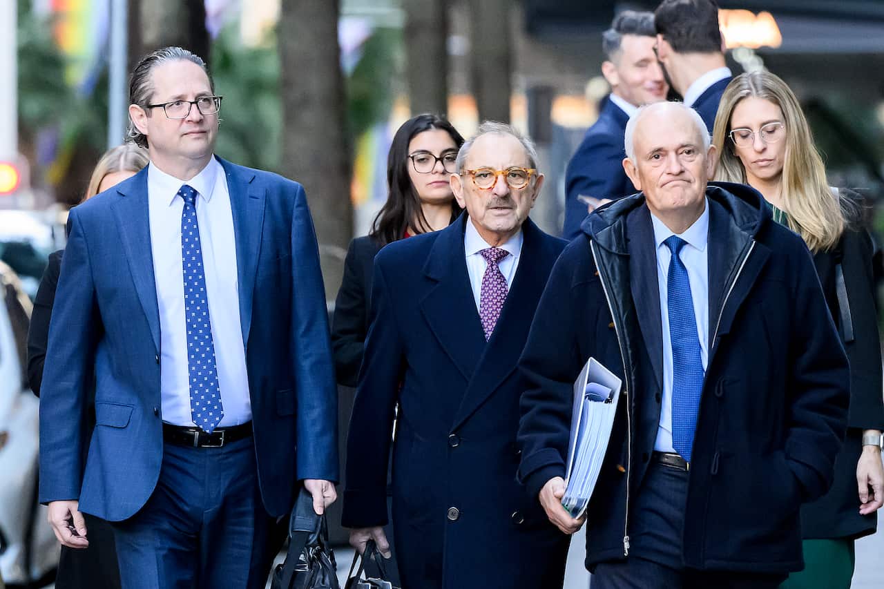 Three men wearing suits walking outside.