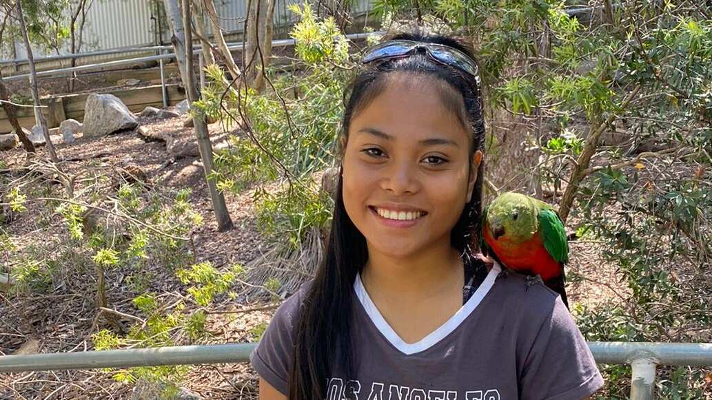 Teenage girl standing outside with a bird on her shoulder