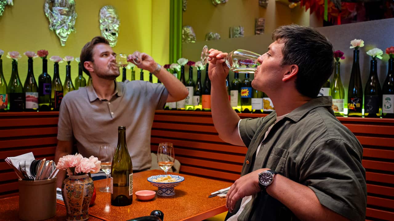 Two men drink wine in a restaurant booth