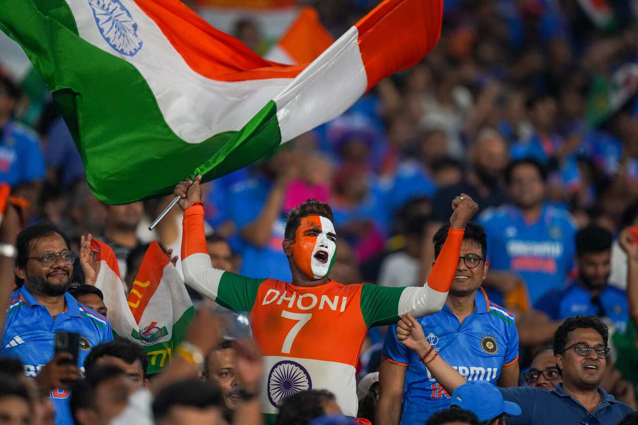A man with the Indian flag painted on his face and shirt celebrates in a stadium