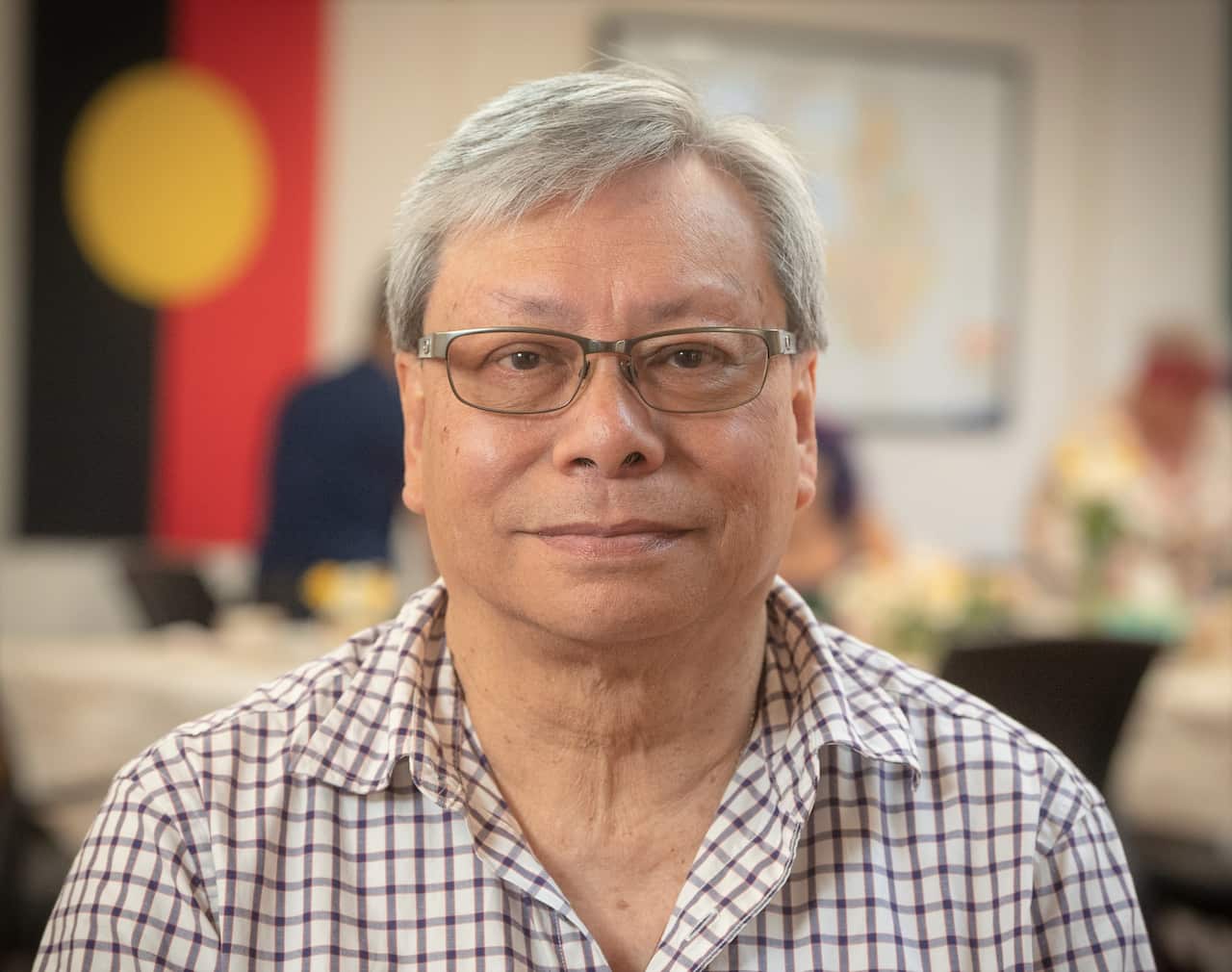 Death cafe participant Eric Yeung sitting in a checked shirt .