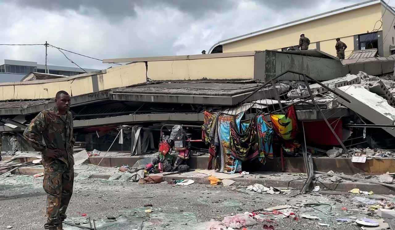 A man standing next to a collapsed building