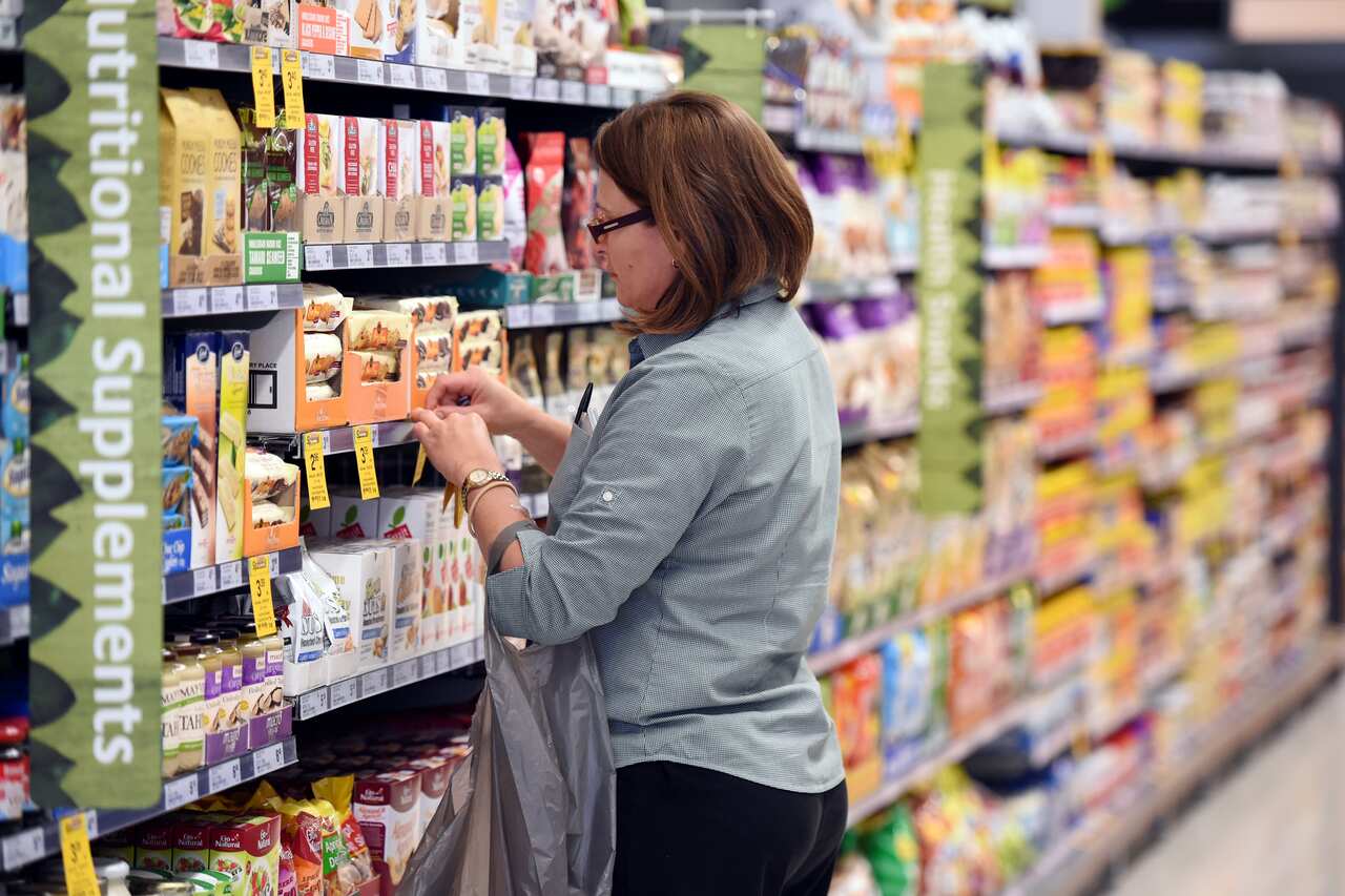 A lady stacking shelves at a asupermarket.
