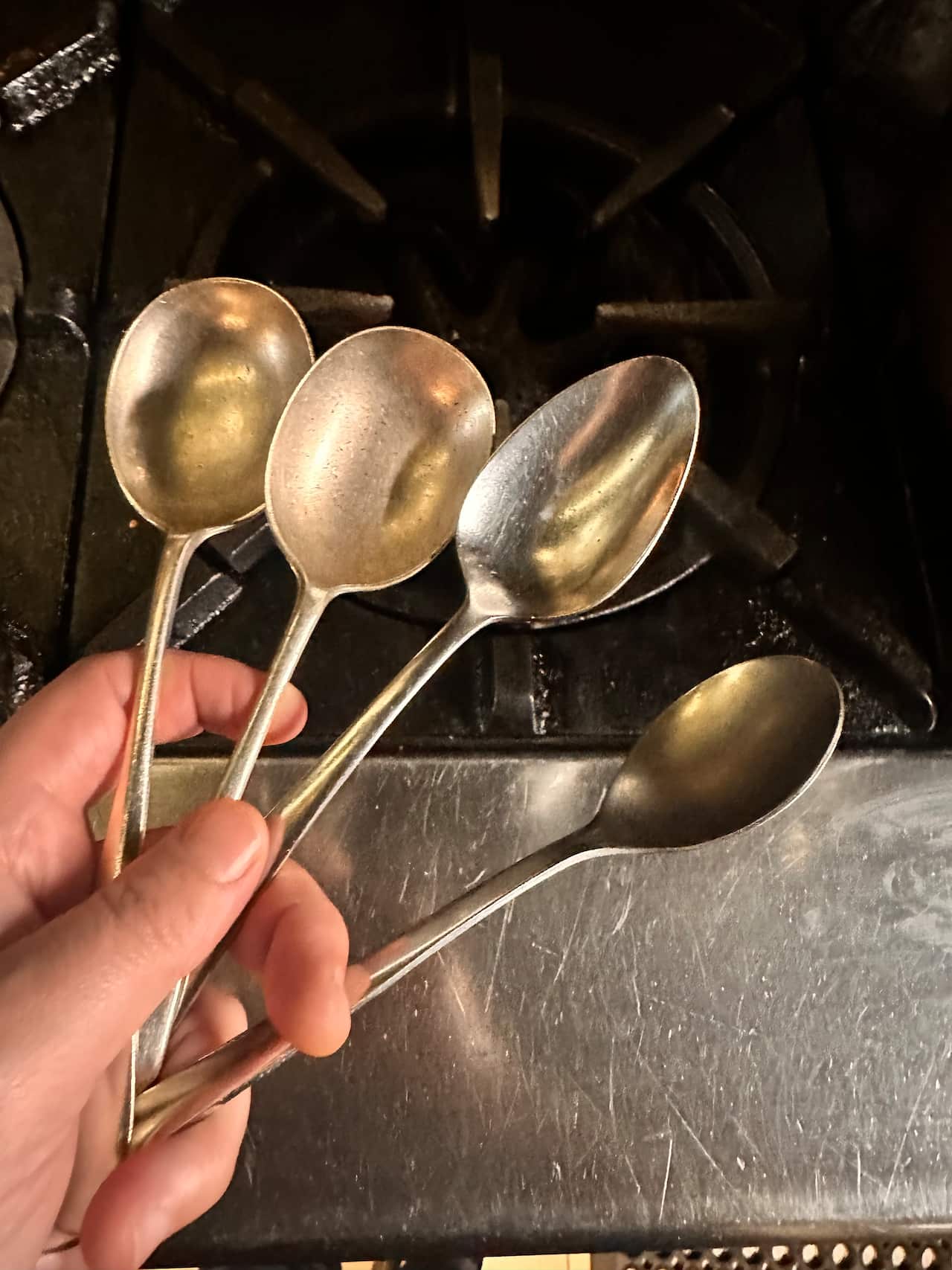 Four spoons being held by a hand.