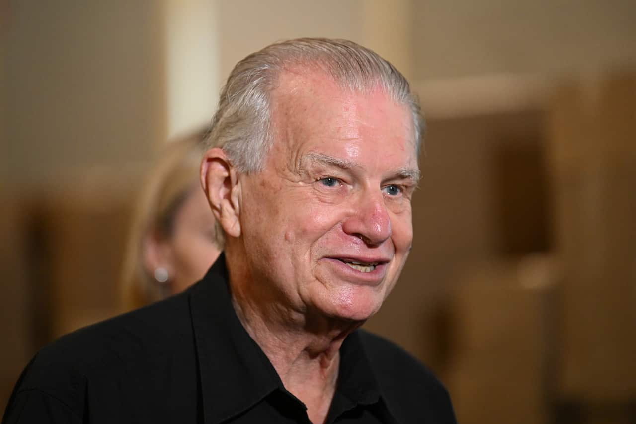 A man with slicked-back grey hair wearing a black shirt