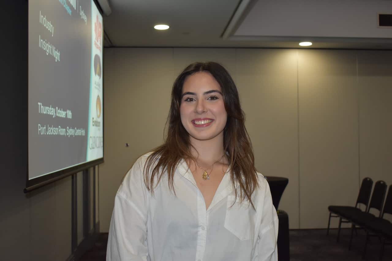 A young woman in a white shirt smiles at the camera.